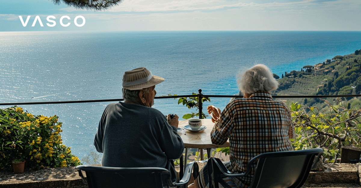 Un couple de seniors prenant un café sur le balcon surplombant la mer.