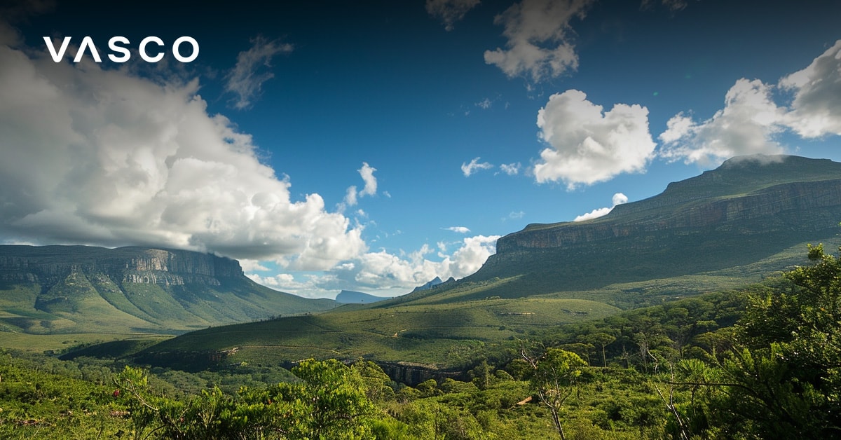 Un vaste paysage vert avec des collines et des montagnes sous un ciel bleu avec des nuages épars.