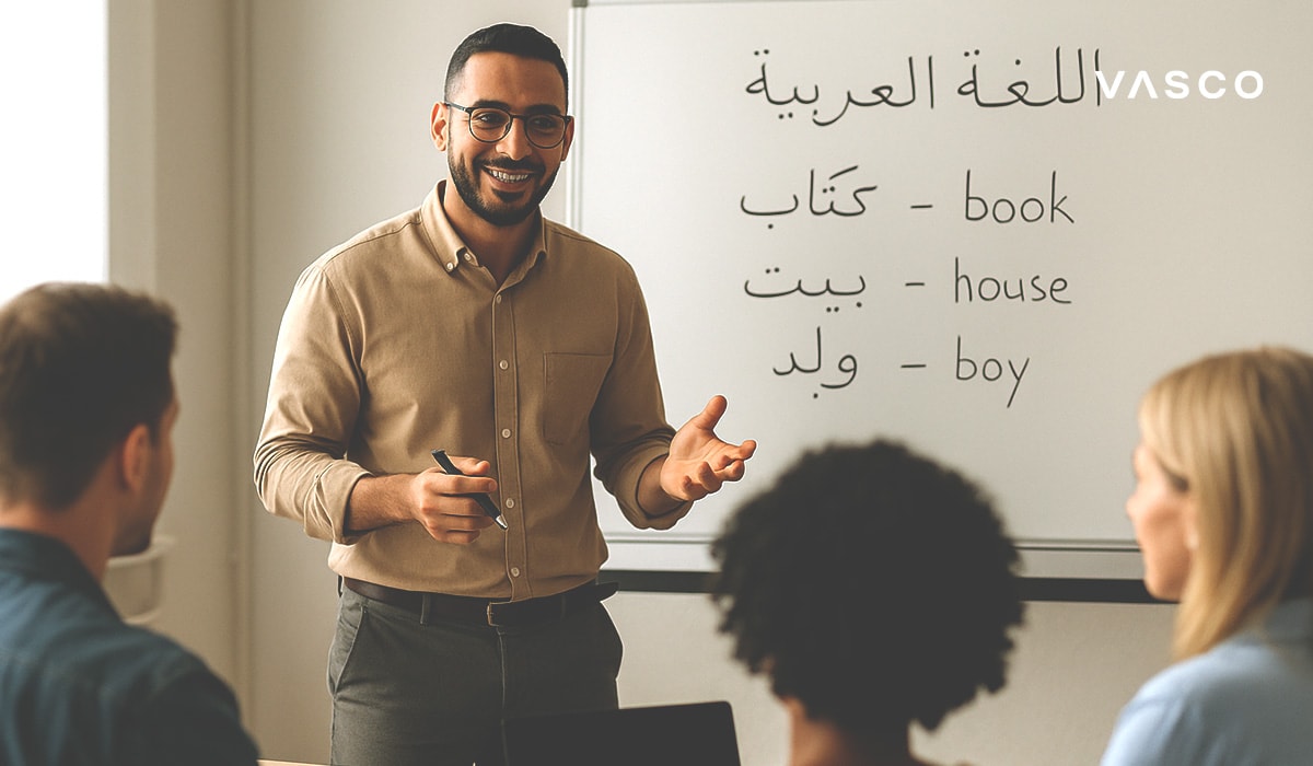 ecris en une phrase courte Un enseignant souriant explique des mots arabes à des étudiants devant un tableau blanc où figurent les mots 