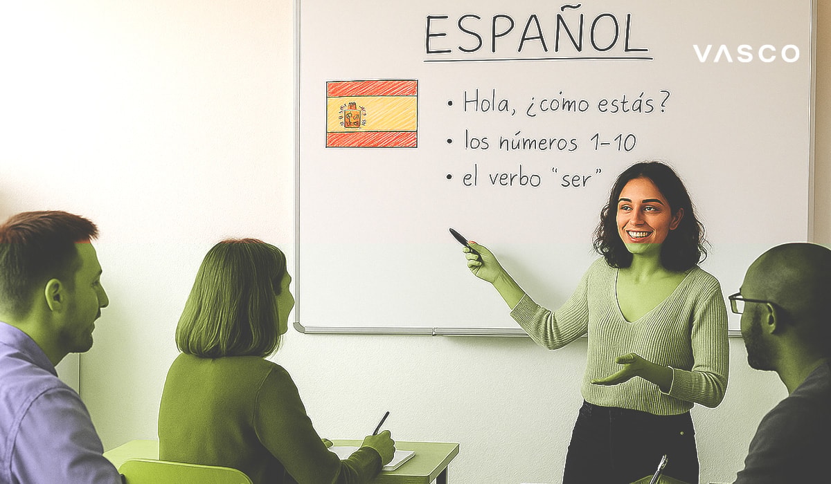  Une professeure souriante, debout devant un tableau blanc, enseigne l'espagnol à trois étudiants assis.