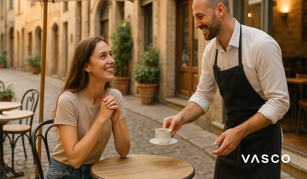 Un serveur servant un café à une femme assise à une table de café en plein air