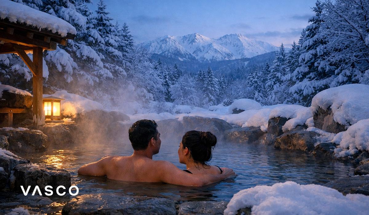 Couple se relaxant dans un onsen japonais traditionnel entouré de montagnes enneigées — voyage au Japon en hiver.