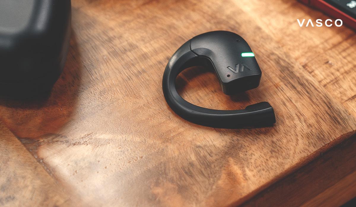 écouteur traducteur vasco en gros plan sur une table en bois avec témoin led