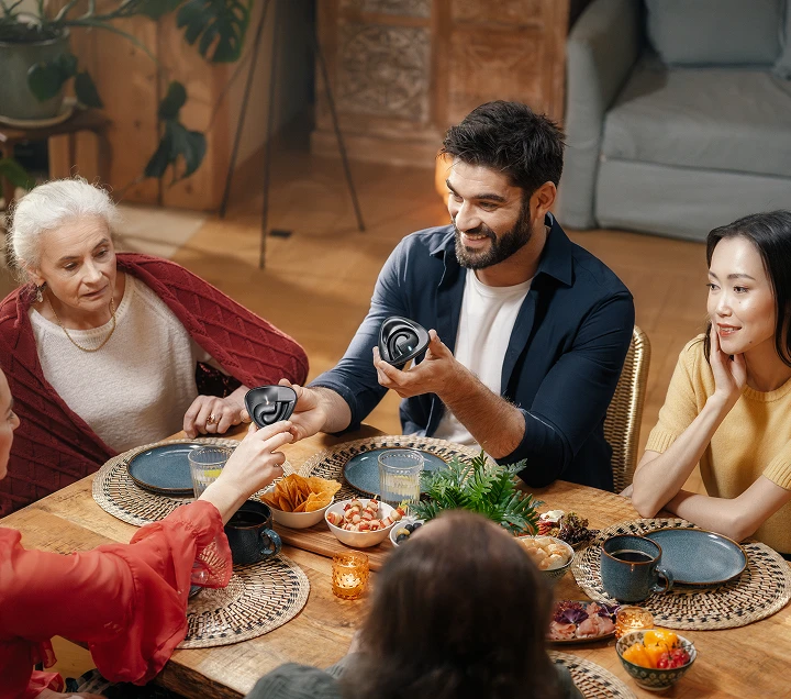 Des personnes de différentes nationalités étaient réunies autour d'une table, savourant un repas et participant à des discussions animées, créant ainsi une ambiance chaleureuse et accueillante tout en se passant les écouteurs Vasco Translator E1.