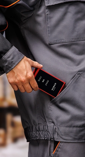 Une personne glisse le Vasco Translator Q1 dans sa poche — un appareil compact réputé pour sa batterie longue durée.